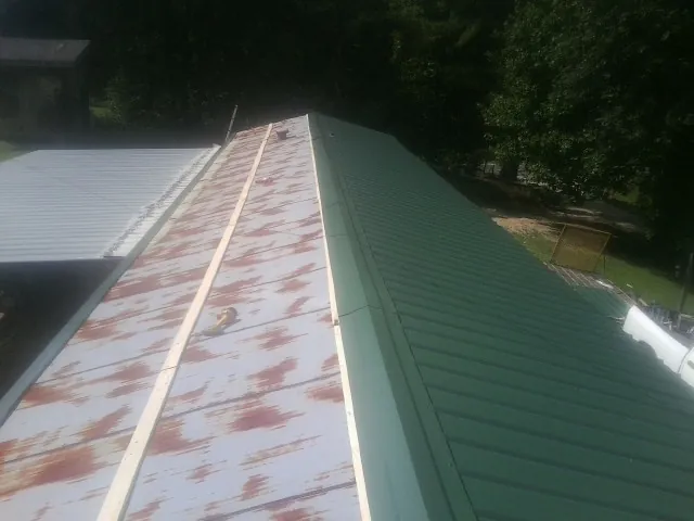 Old rusted panels beside newly installed green metal roofing — Wind Damage Roof Repair by Roofing Brothers in Bay Village