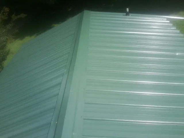 New green metal panels meeting at the ridge of a roof — Flat Roof Repair work by our crew in Bay Village