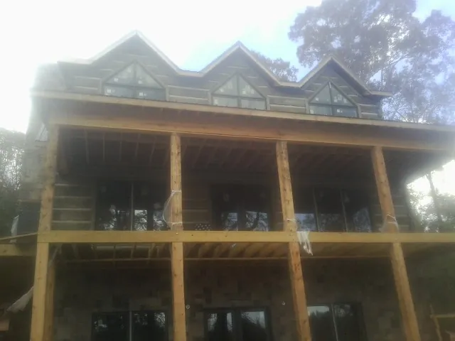 Dormers and porch framing on a large log home under construction — Roof Coating work by our crew in Bay Village