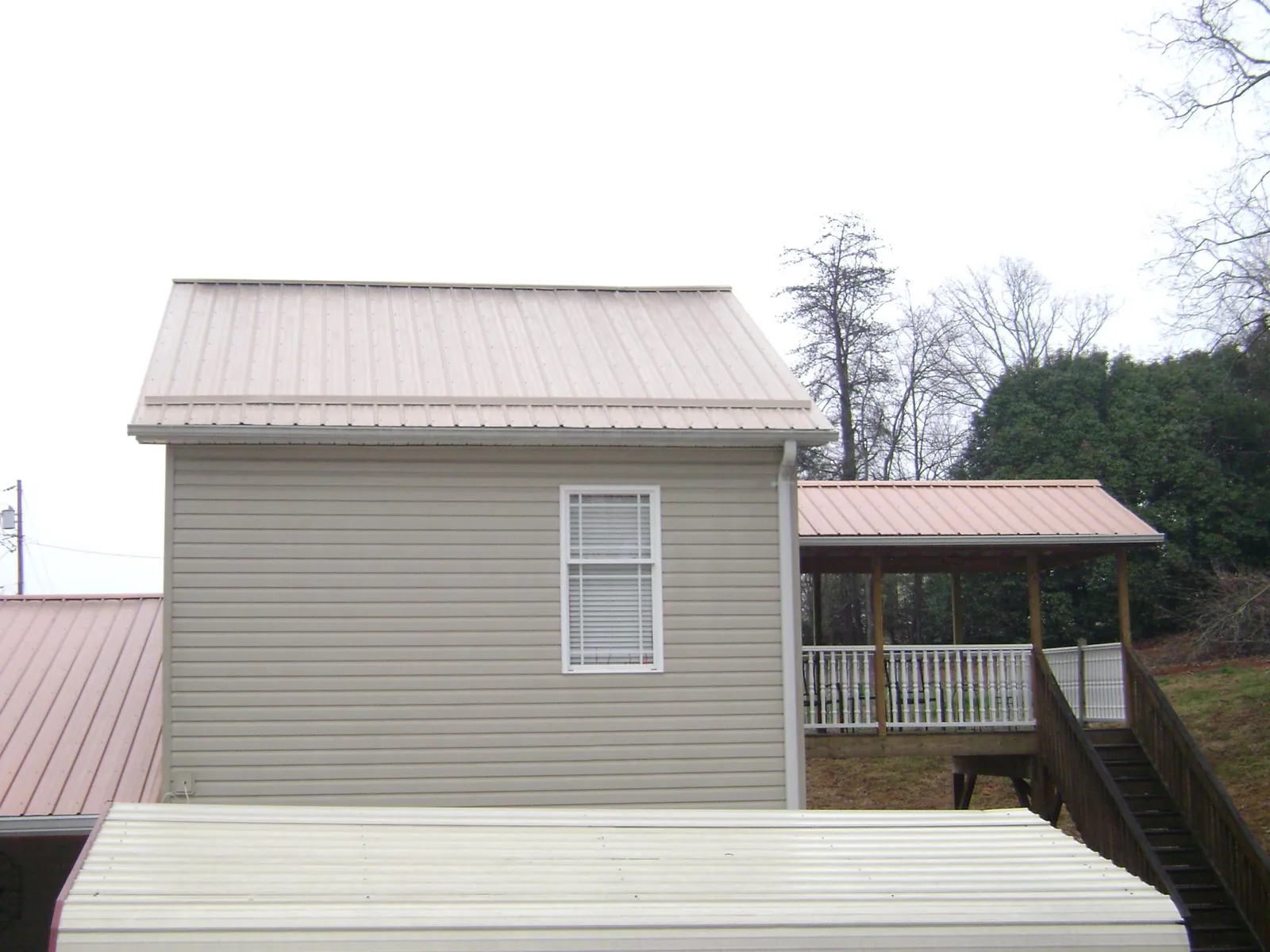 Tan metal roofs on a two story addition and attached porch, from a Roof Replacement job in Bay Village