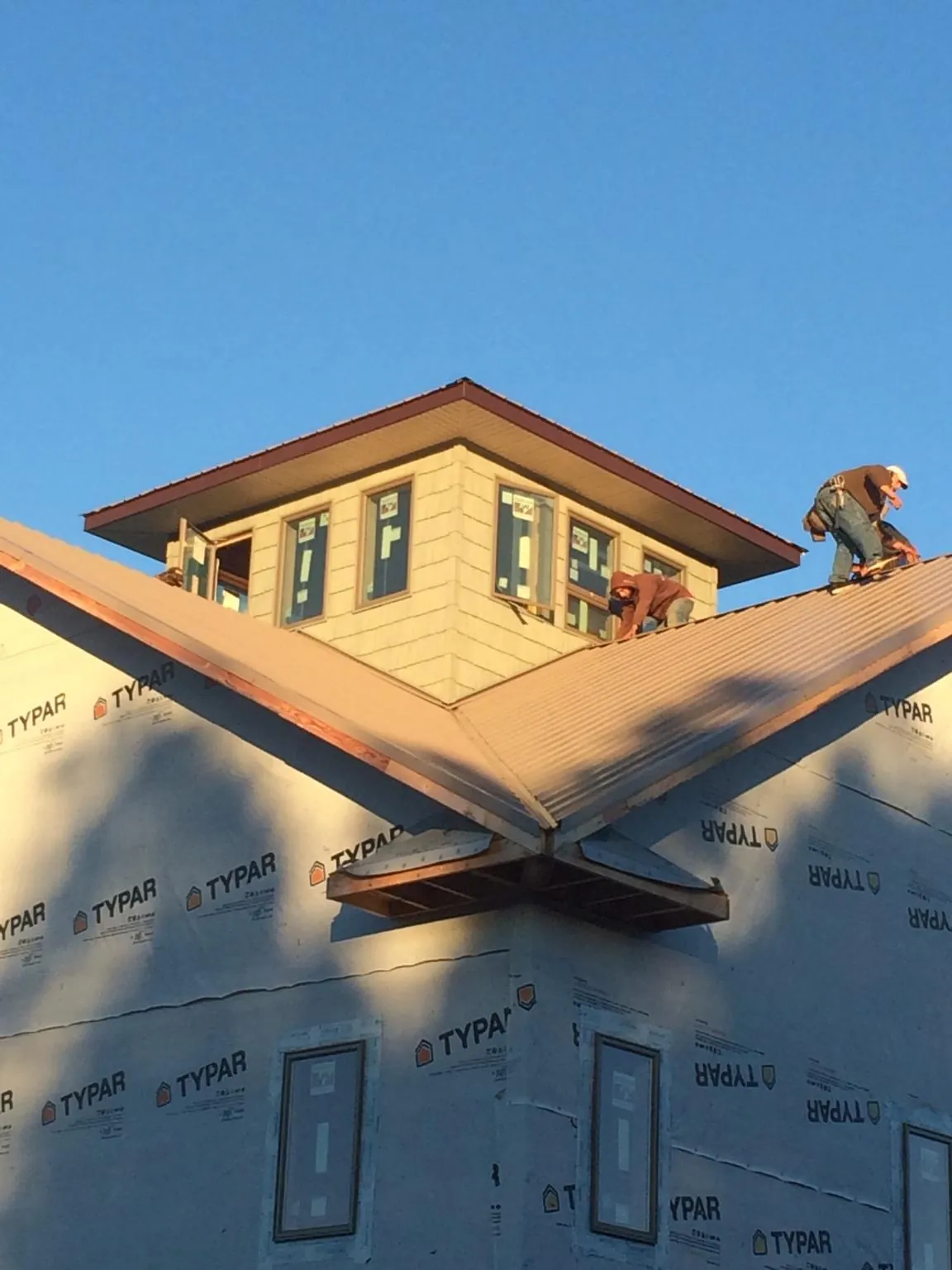 Roofers working around a rooftop cupola on a new metal roof at sunset — Roof Waterproofing in Bay Village by Roofing Brothers